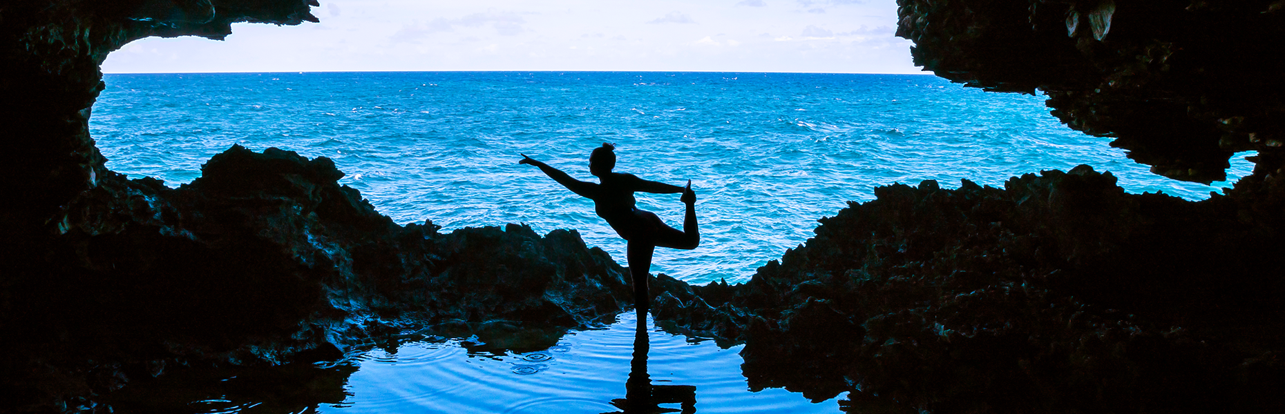 Silhouette of a person in a yoga pose beside the sea