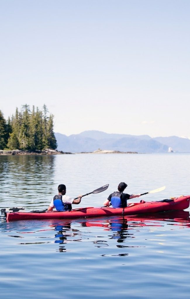 Two kayakers paddling calm water in Southeast Alaska