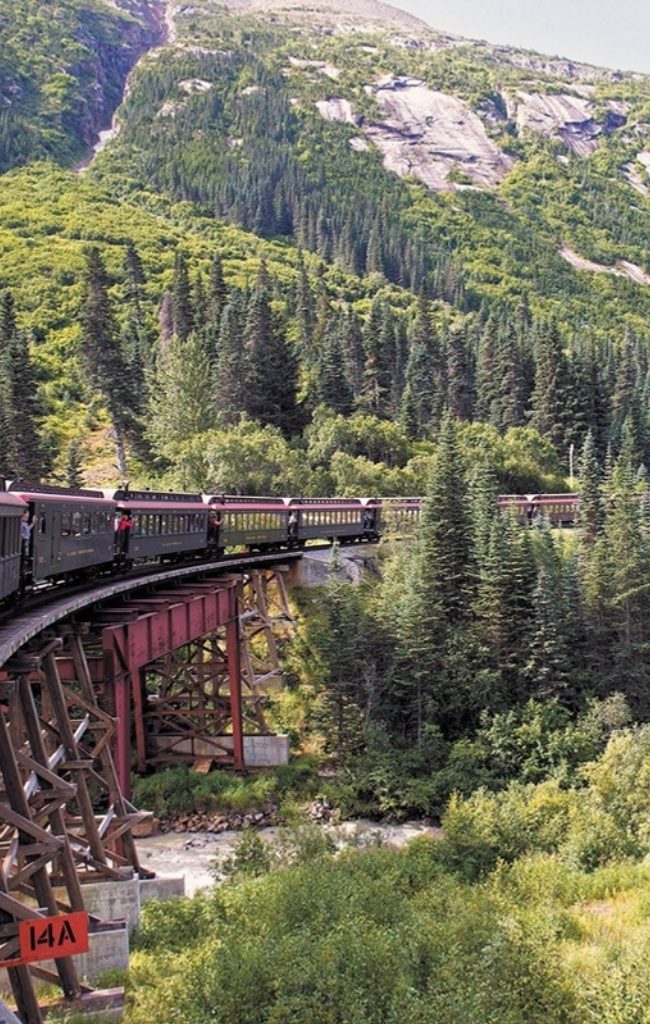 A vintage train crossing a trestle bridge on the White Pass route