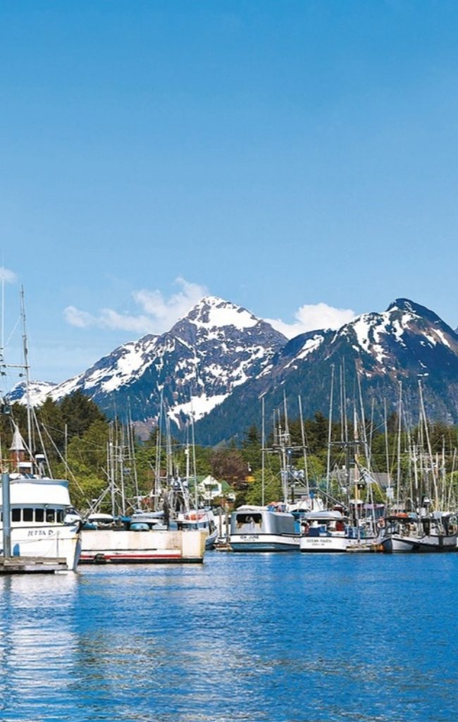 Fishing boats in a harbor below snow-capped mountains in Southeast Alaska
