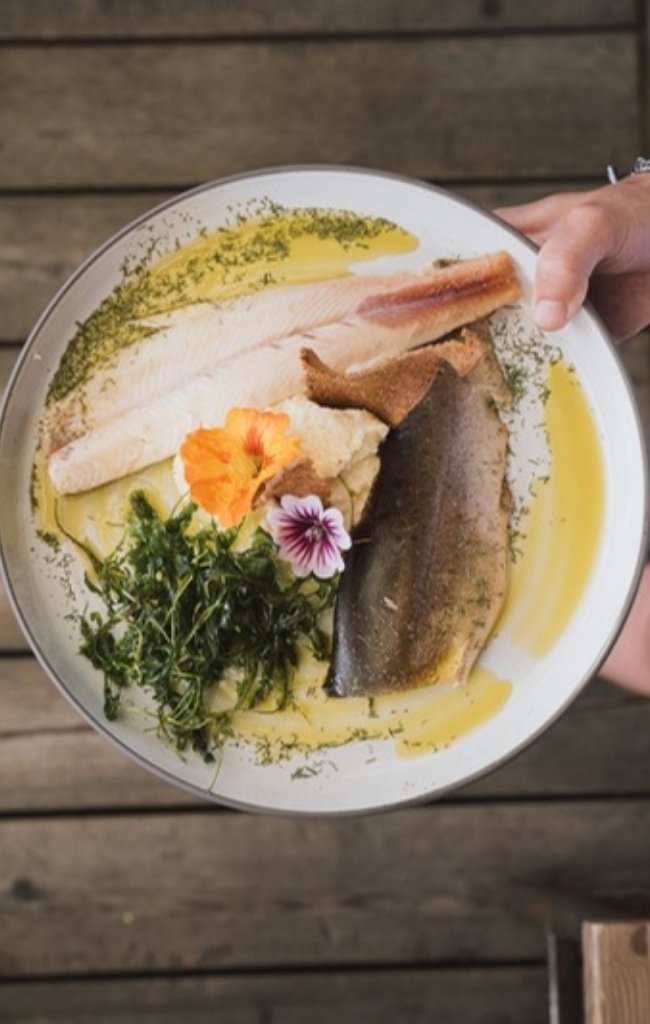 A plate of fresh trout with herbs and edible flowers