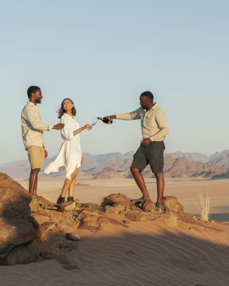 Friends toasting with sparkling wine on a desert dune