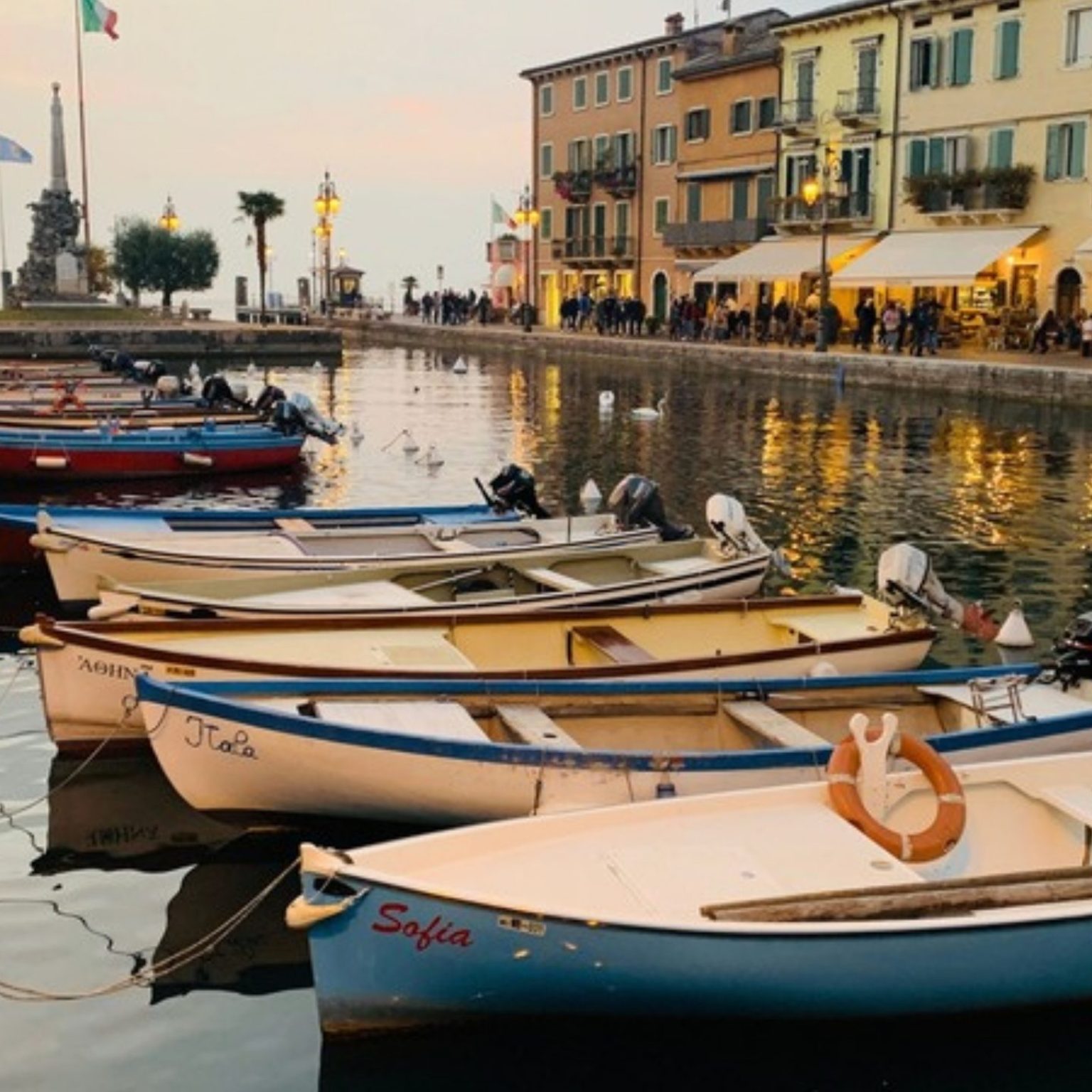 Boats moored along a lantern-lit harbor at dusk