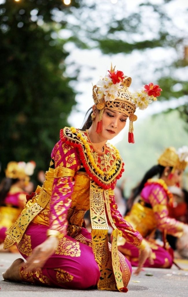 A Balinese dancer in traditional dress performing outdoors