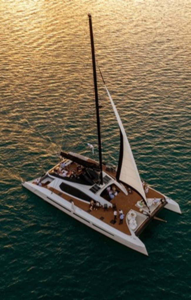 A catamaran sailing on calm water at sunset