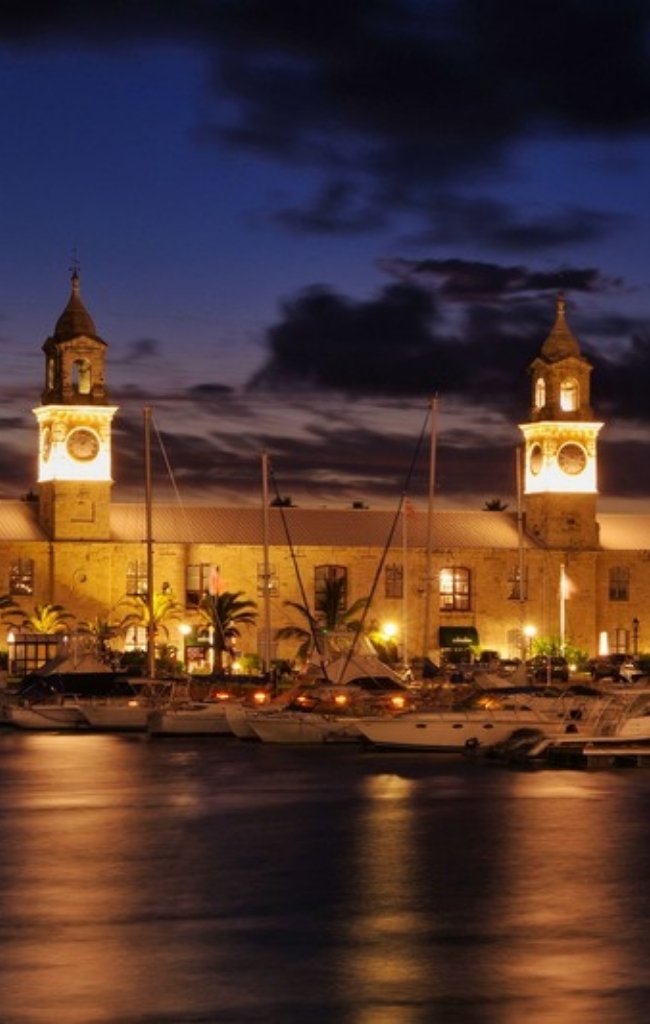 The twin towers of the Clocktower Building lit up at night at the Royal Naval Dockyard