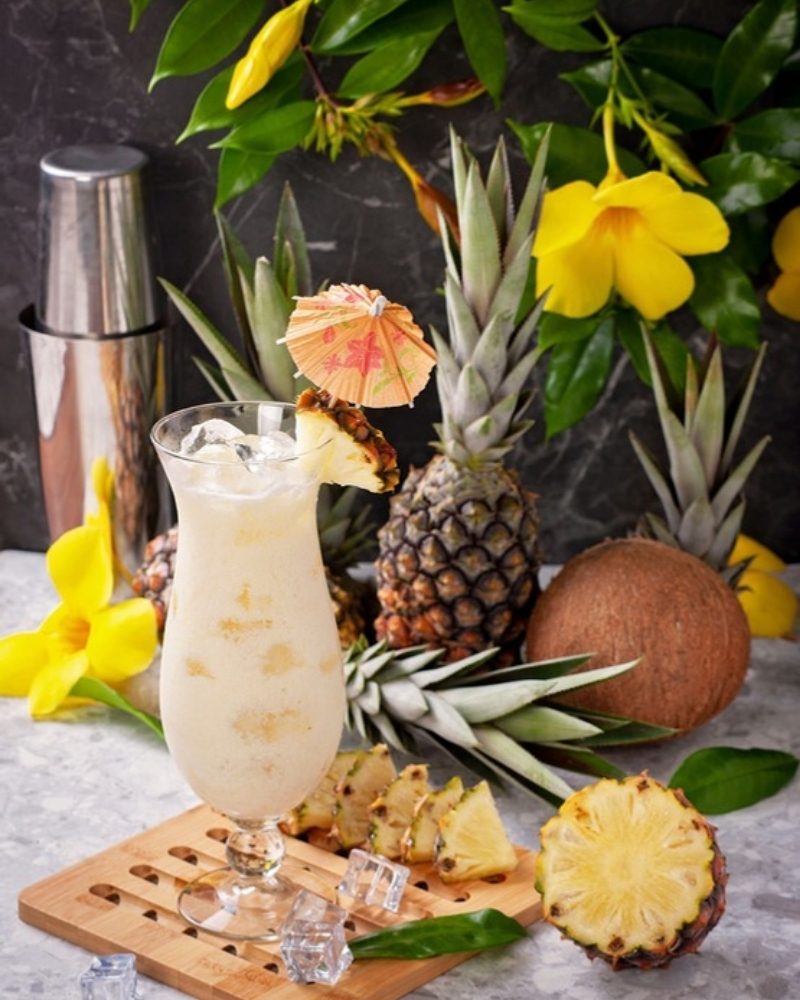 Tropical cocktail with fresh pineapple, coconut and flowers