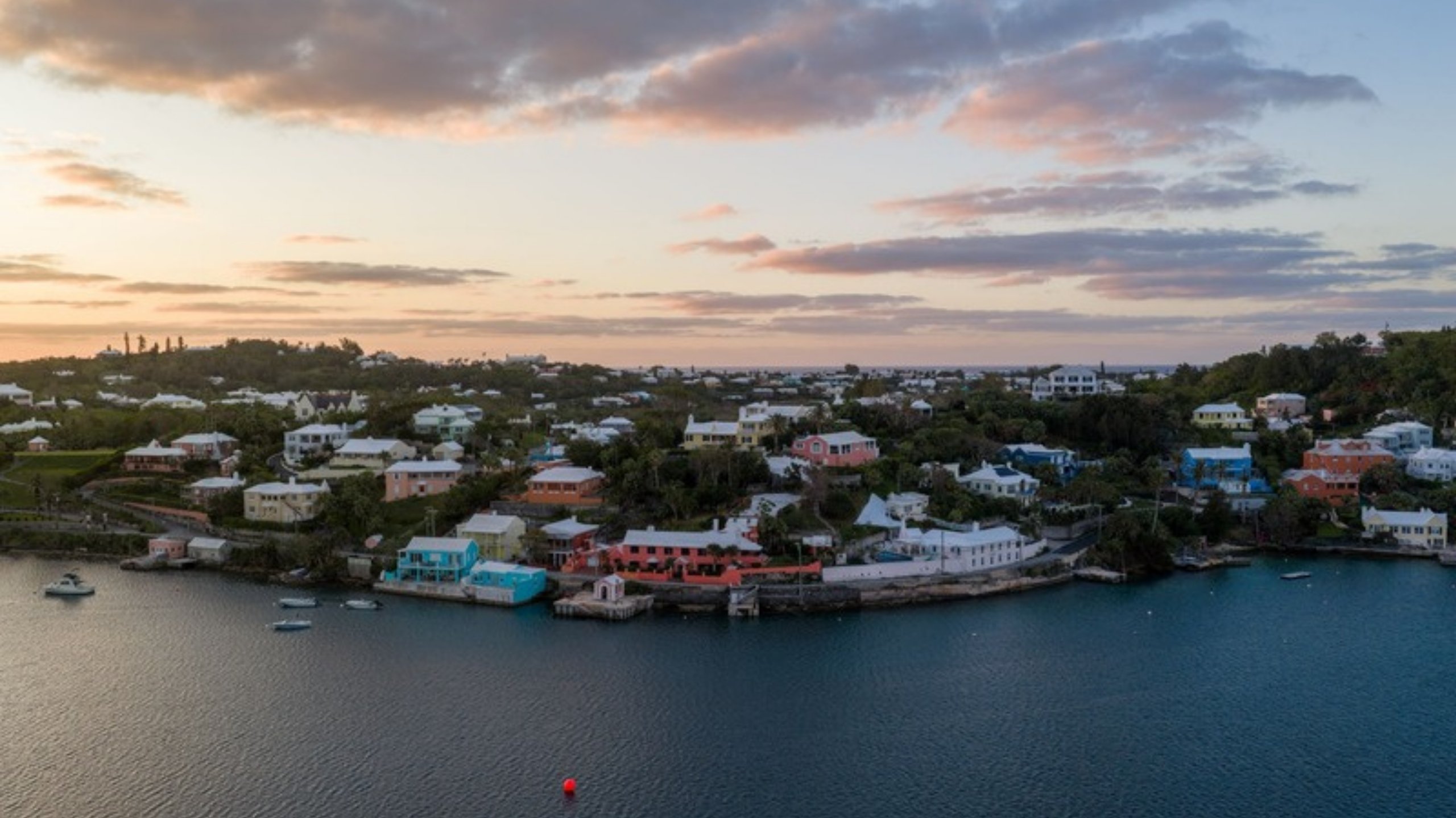 Pastel homes along a Bermuda harbor at sunset