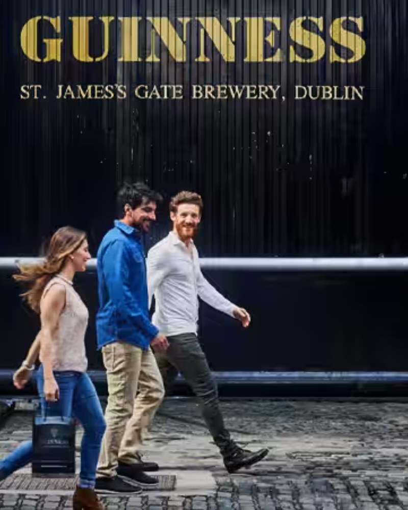Friends walking past the gate of the Guinness brewery at St. James's Gate, Dublin