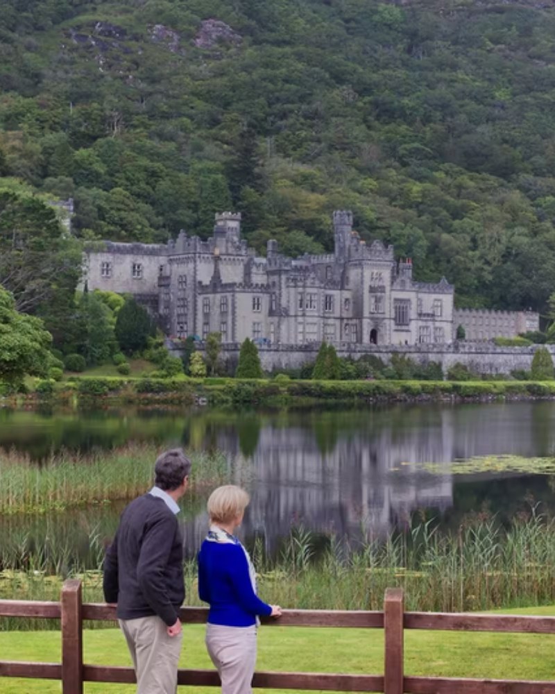 A couple looking across the lake at Kylemore Abbey in Ireland