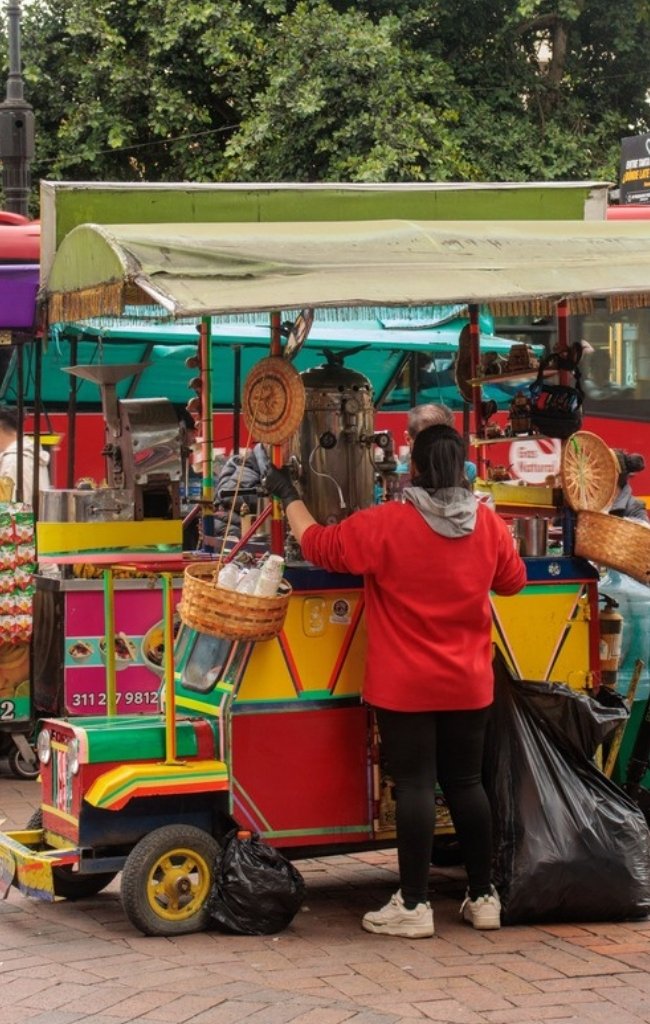 A colorful street food cart and vendor in Bogotá