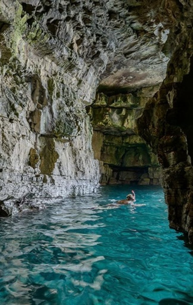 A swimmer in a turquoise sea cave on the coast of Istria