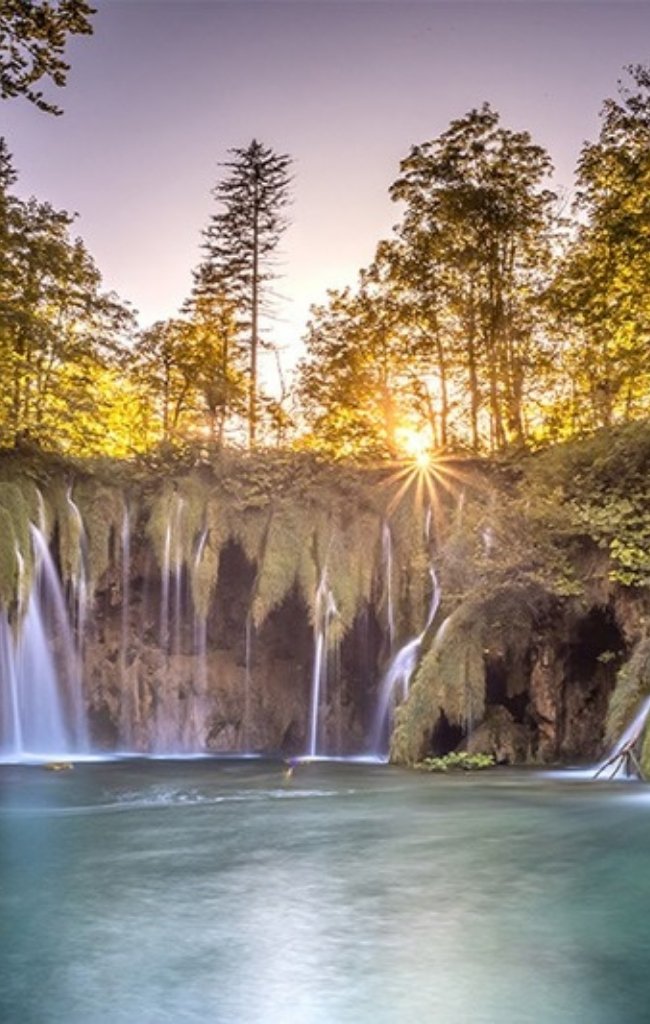 Waterfalls pouring into an emerald lake at Plitvice Lakes National Park