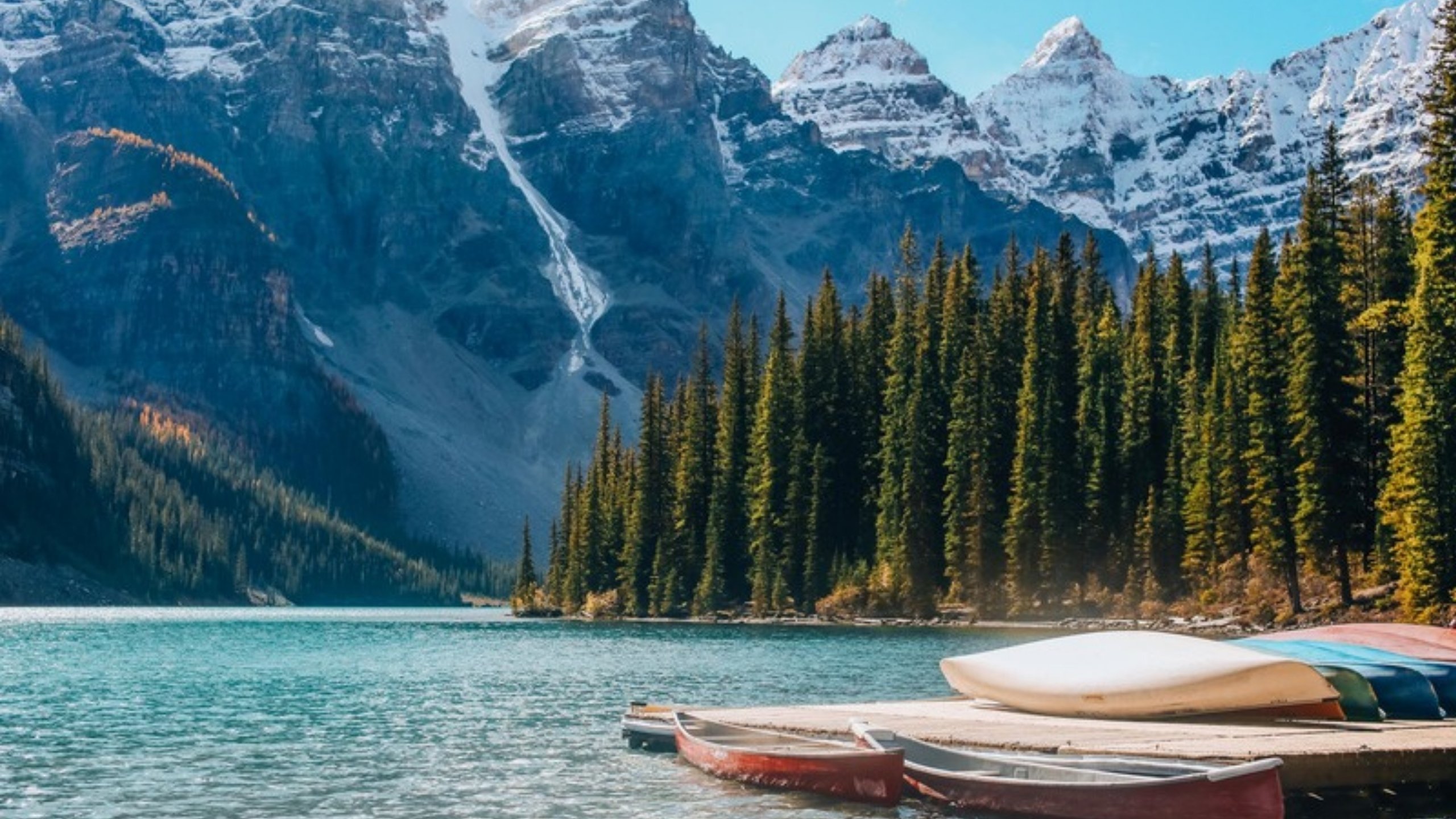 Canoes on a turquoise lake below snowy peaks in Banff National Park