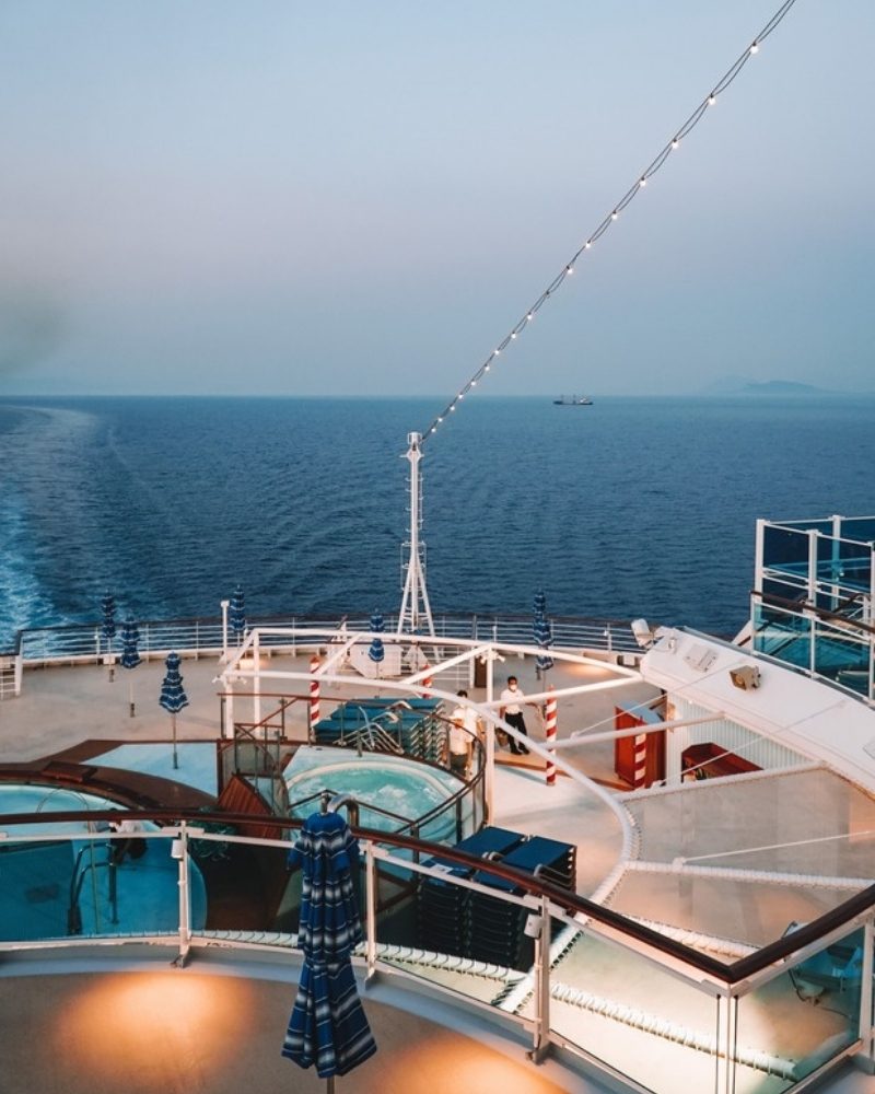 Cruise ship pool deck at dusk with the sea beyond