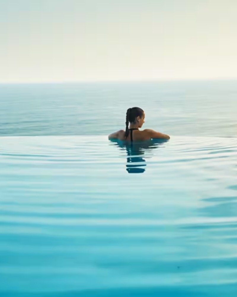 A woman in an infinity pool overlooking the ocean