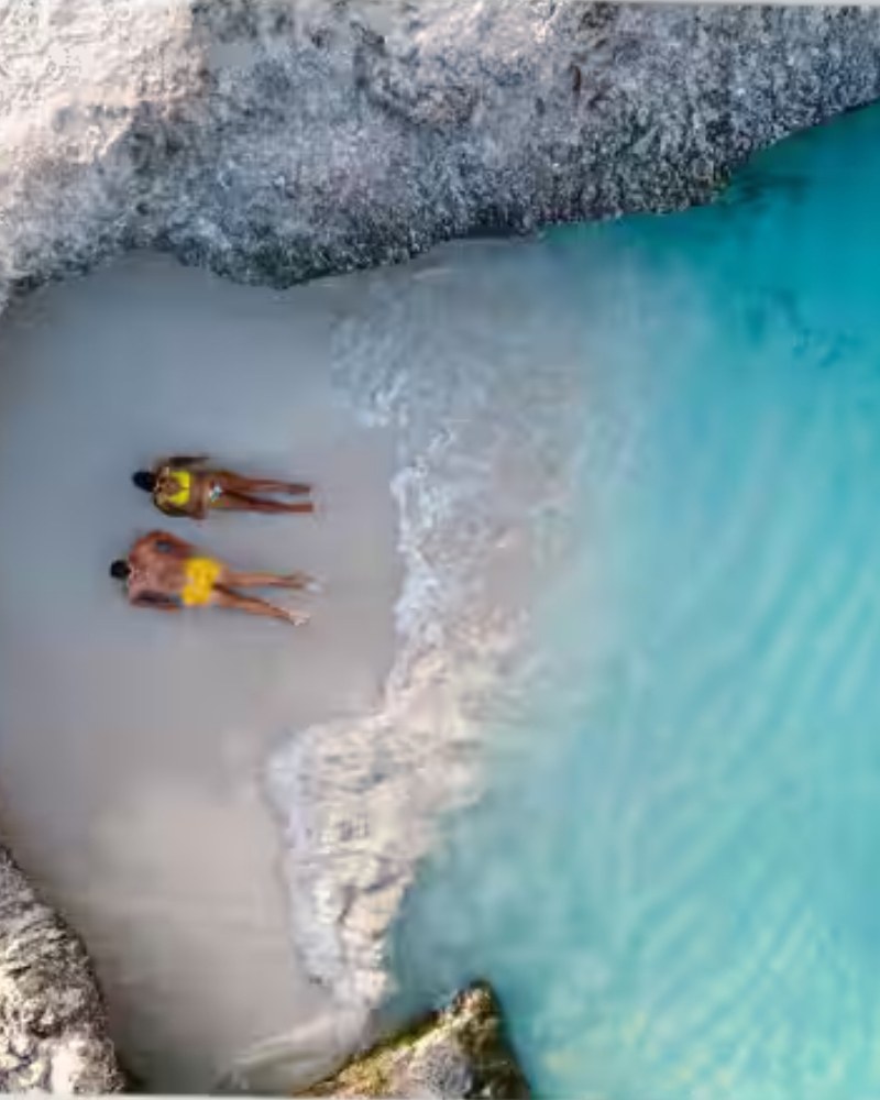 Aerial view of a couple lying on a small beach cove
