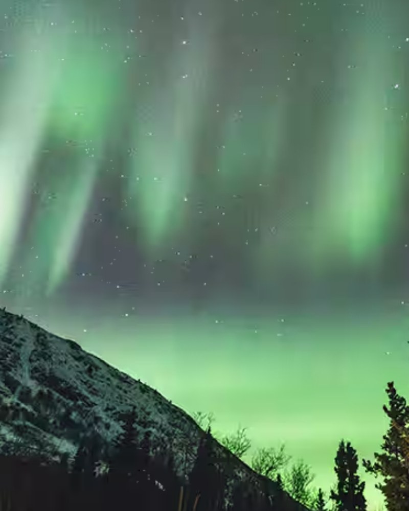 The northern lights over a snowy mountain in the Yukon