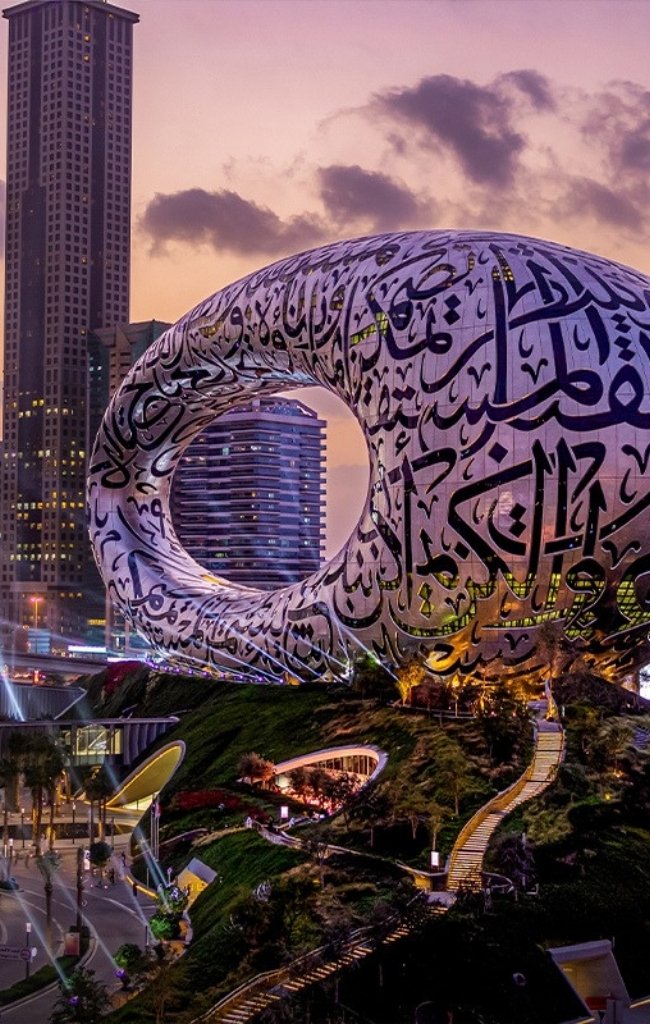 The Museum of the Future lit at dusk below downtown towers