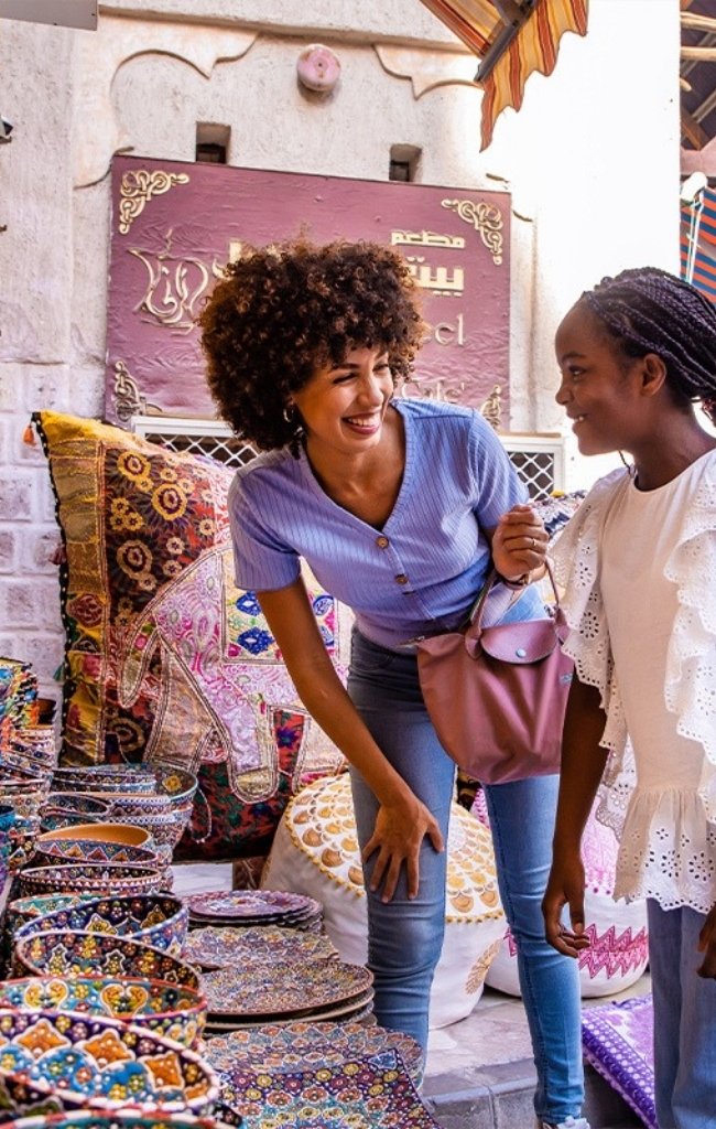 Two travelers browsing colorful ceramics in a souk