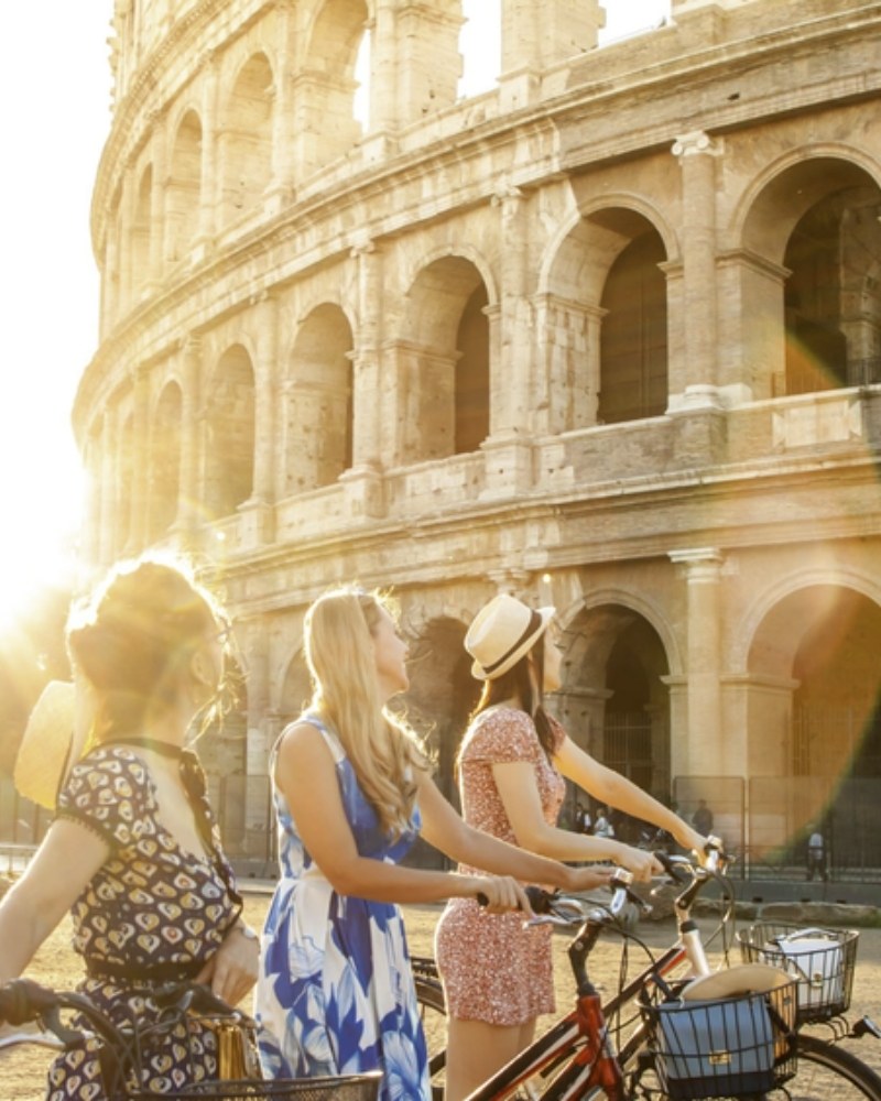 Friends with bicycles outside the Colosseum in Rome at sunset