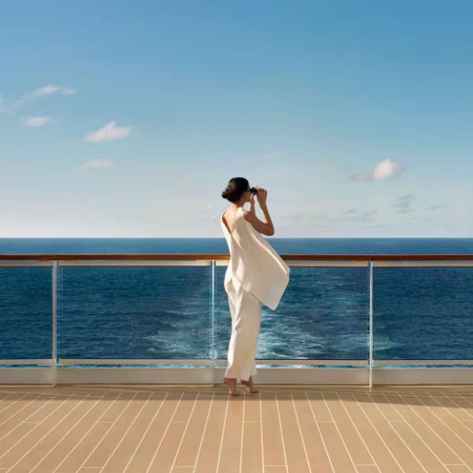 A guest looking out to sea from the deck of an Explora Journeys ship