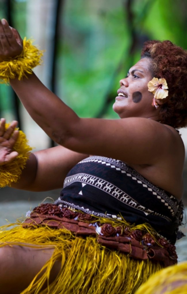 Fijian dancers in traditional dress performing a seated dance