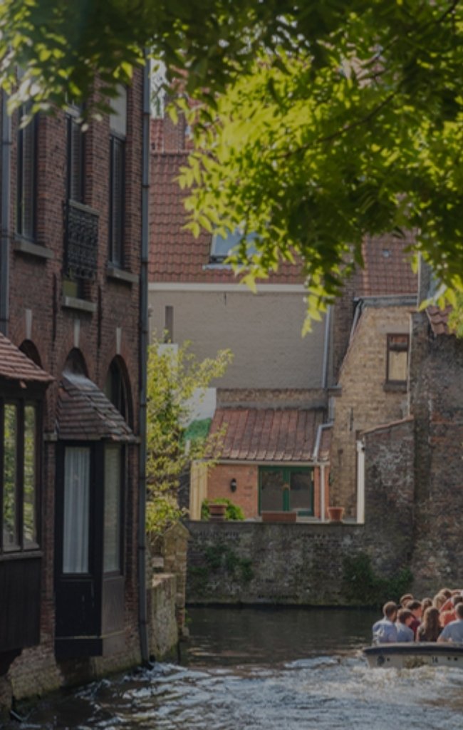 A canal boat passing old brick houses in Bruges