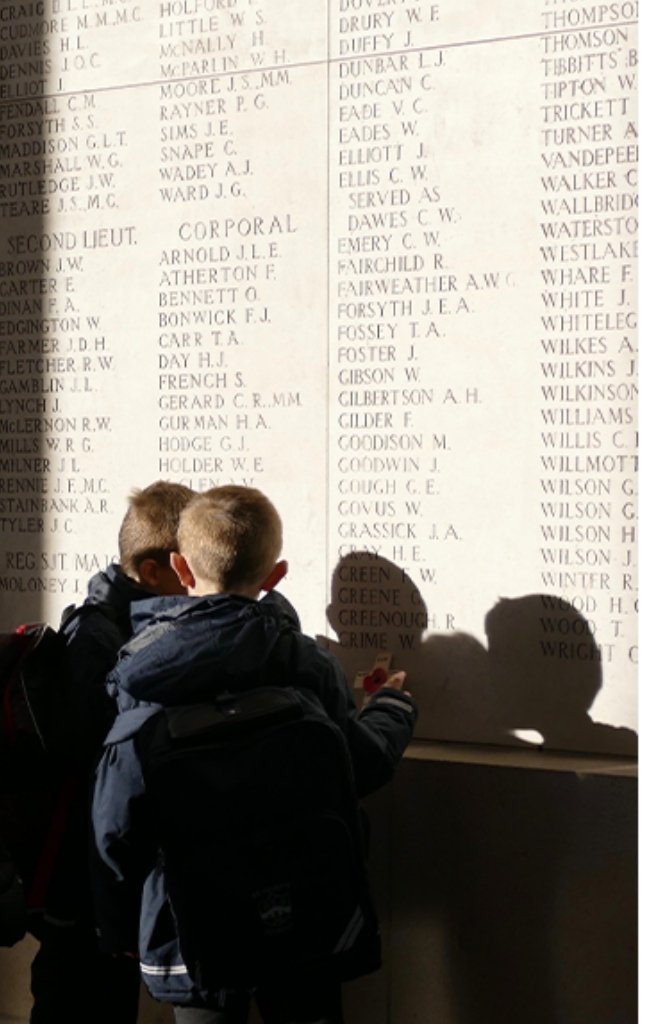 Children reading names on a World War I memorial wall in Flanders