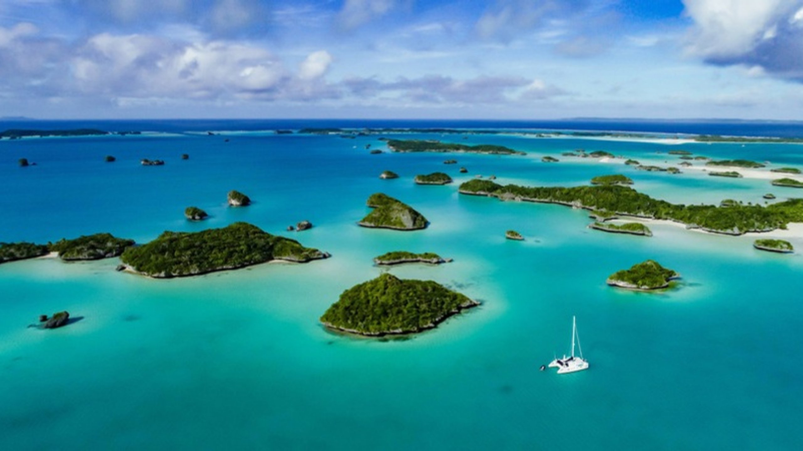 A catamaran at anchor among green islets in Fiji's Lau Group