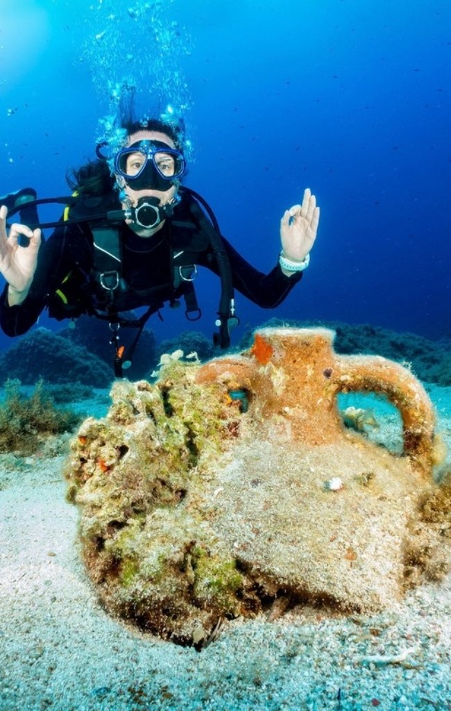 A scuba diver beside an ancient amphora on the seabed