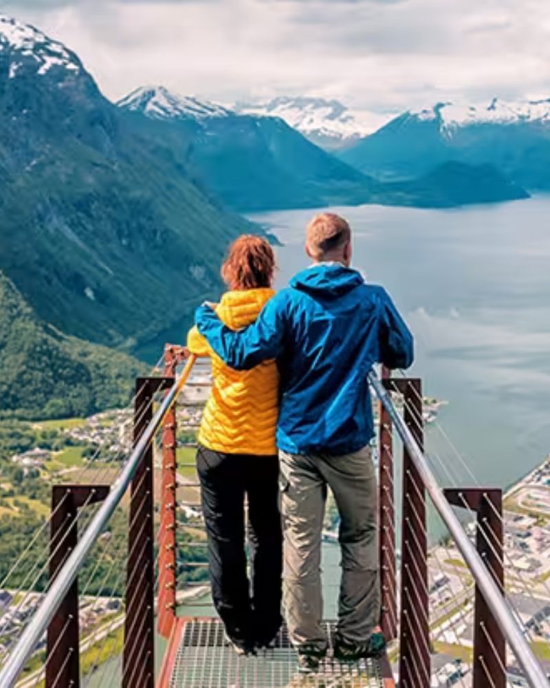 Two travelers at a viewpoint above a Norwegian fjord