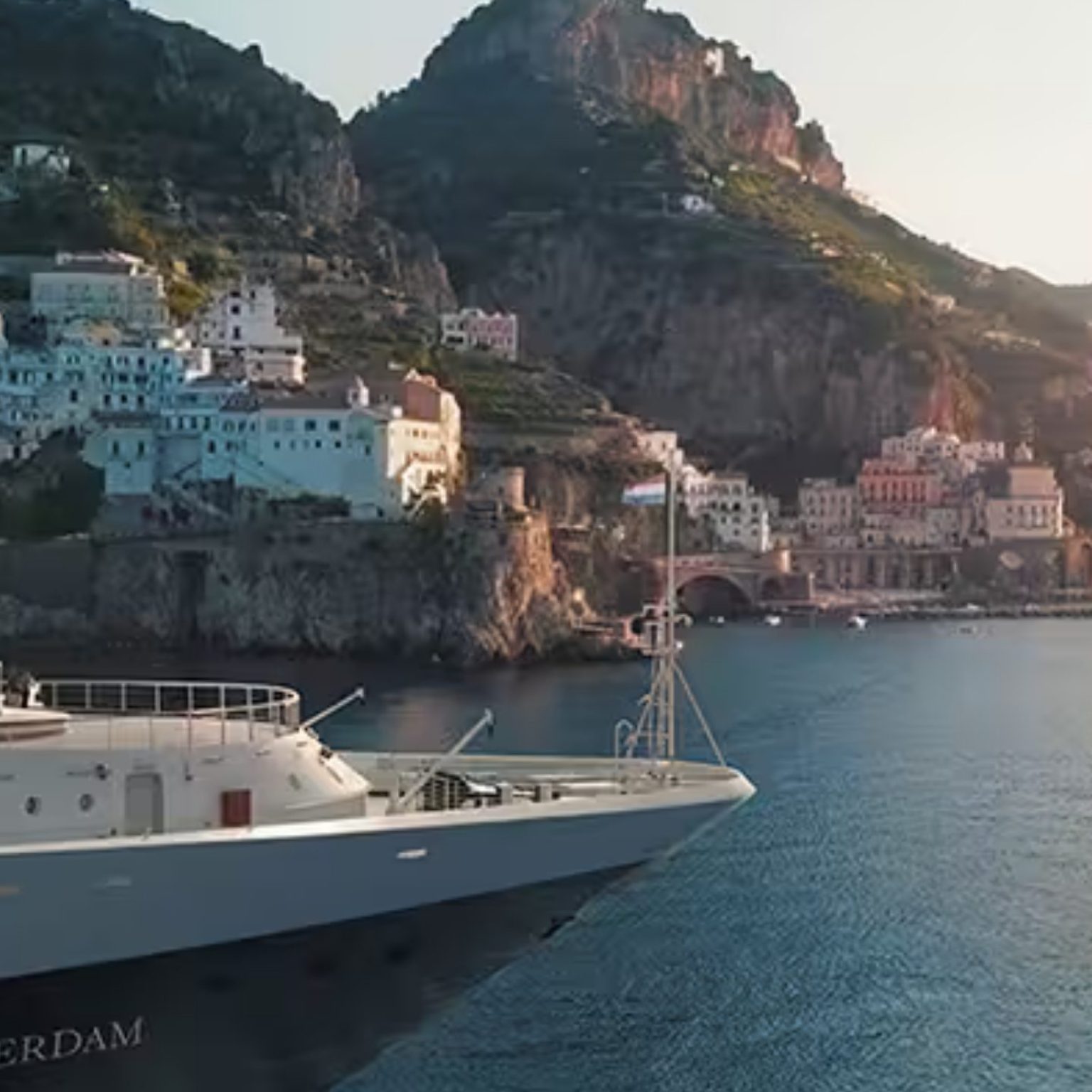 Holland America Line's Rotterdam sailing past a cliffside coastal town