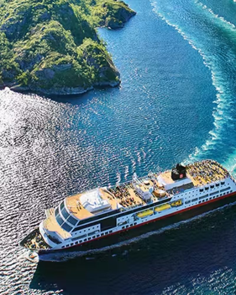 Aerial view of a coastal ship sailing past a green island