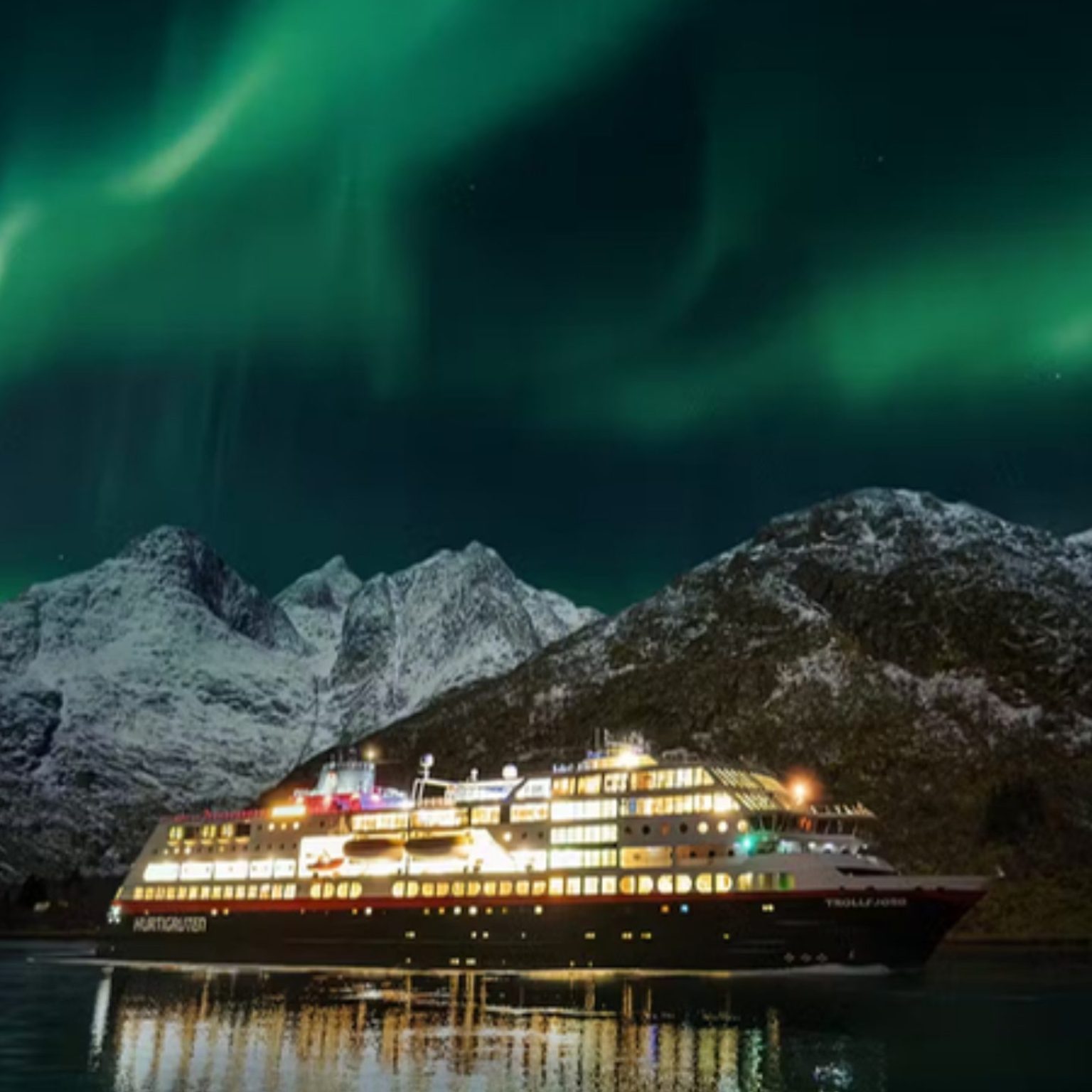 A Hurtigruten ship under the Northern Lights in a Norwegian fjord