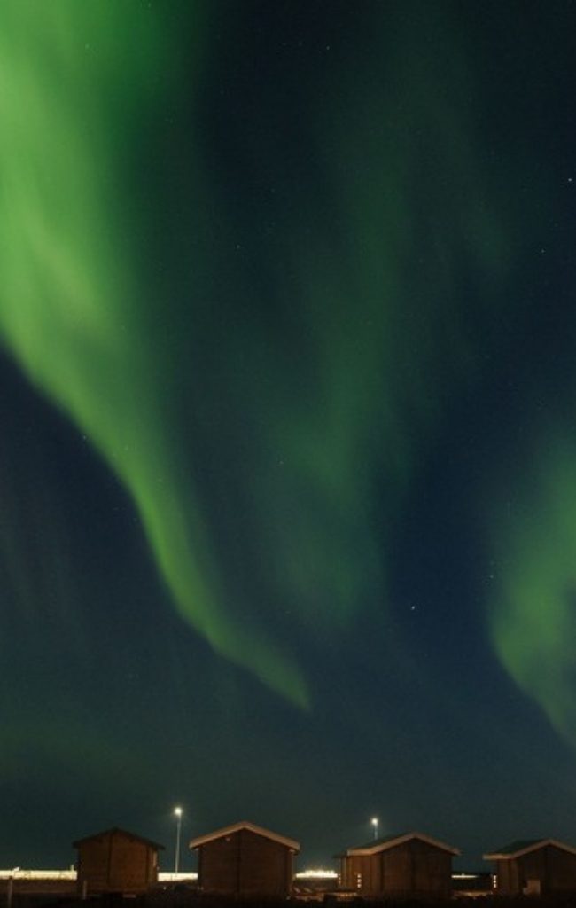 The northern lights over cabins in the Icelandic countryside