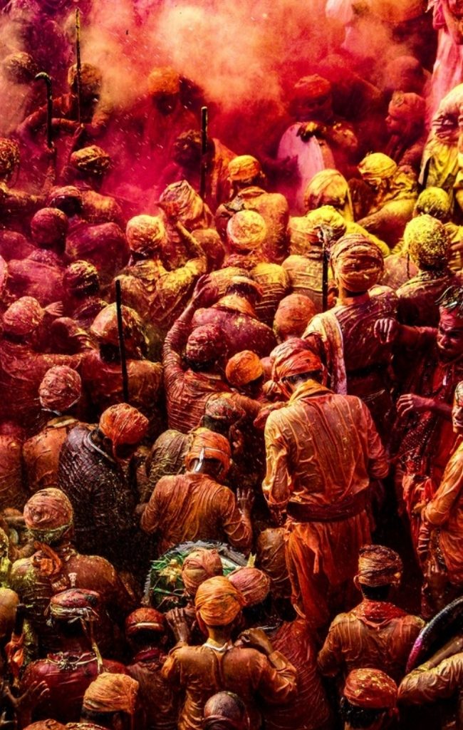 A crowd celebrating Holi with colored powder