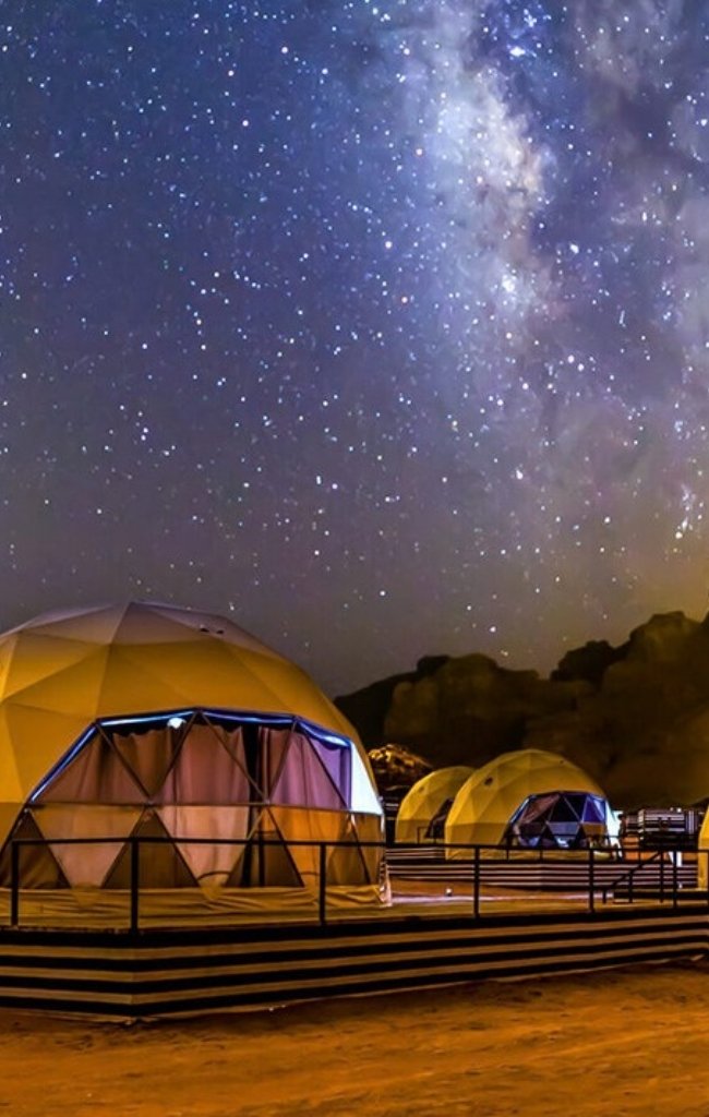 Glowing dome tents under the Milky Way in Wadi Rum
