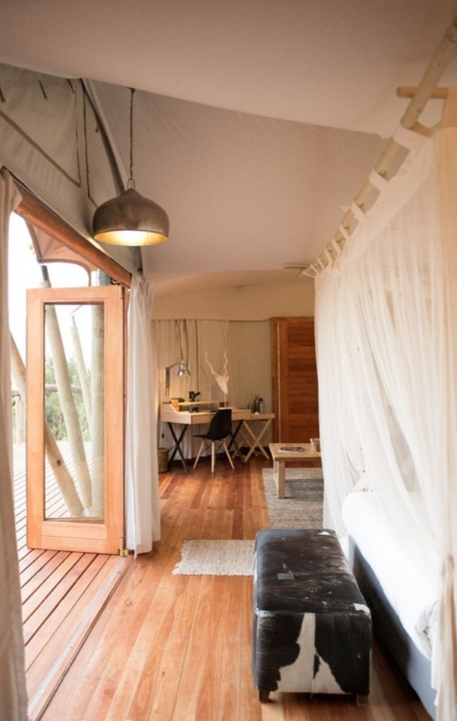 The interior of a canvas safari tent with a wooden floor