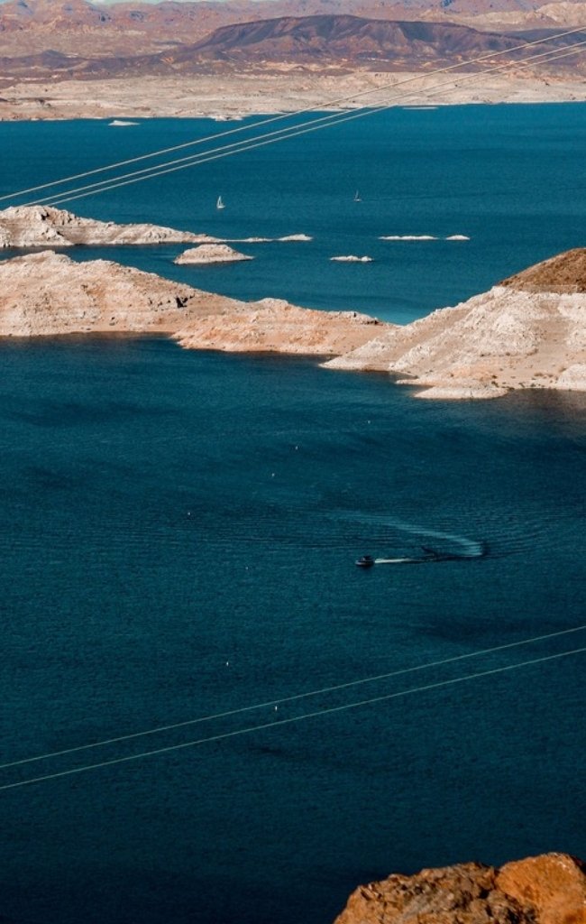 A boat crossing the blue water of Lake Mead between desert ridges