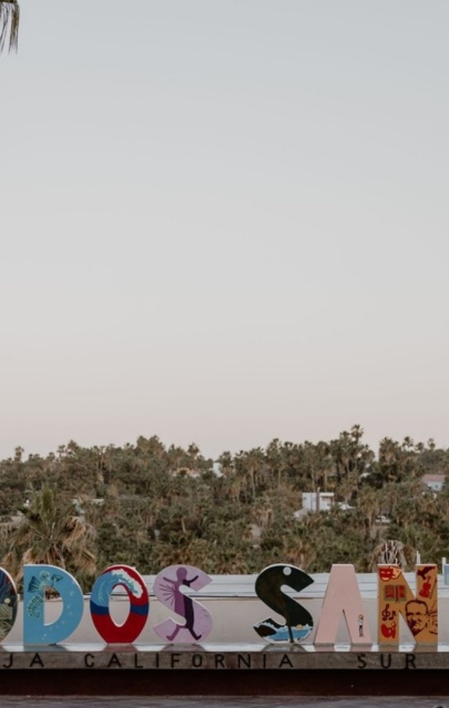 The colorful Todos Santos town sign beneath palm trees