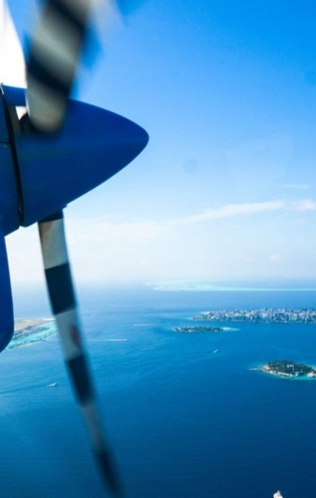 A seaplane flying over blue water and green islands