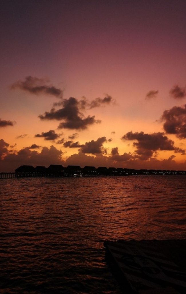 Overwater villas silhouetted at sunset