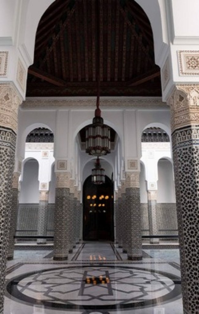 A grand tiled hall with carved columns and a lantern