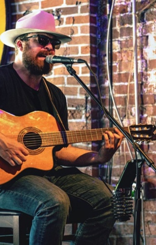 A musician playing acoustic guitar on a small stage