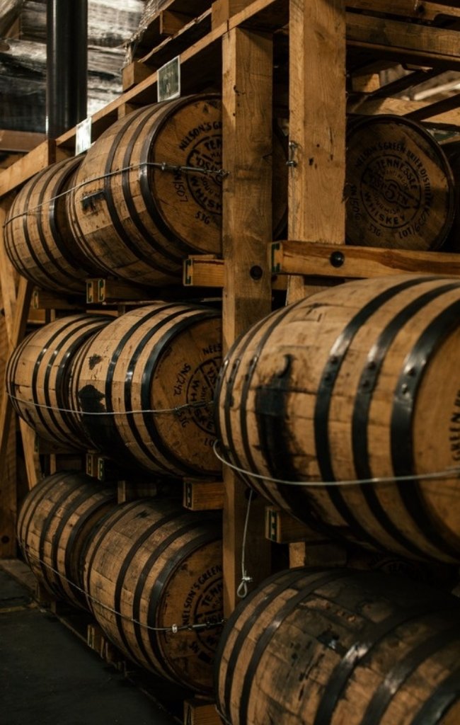 Whiskey barrels stacked in a distillery rickhouse