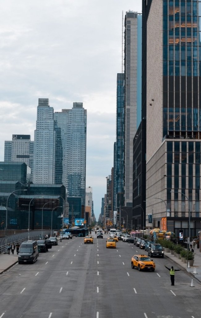 Yellow taxis on a wide avenue lined with towers in Manhattan