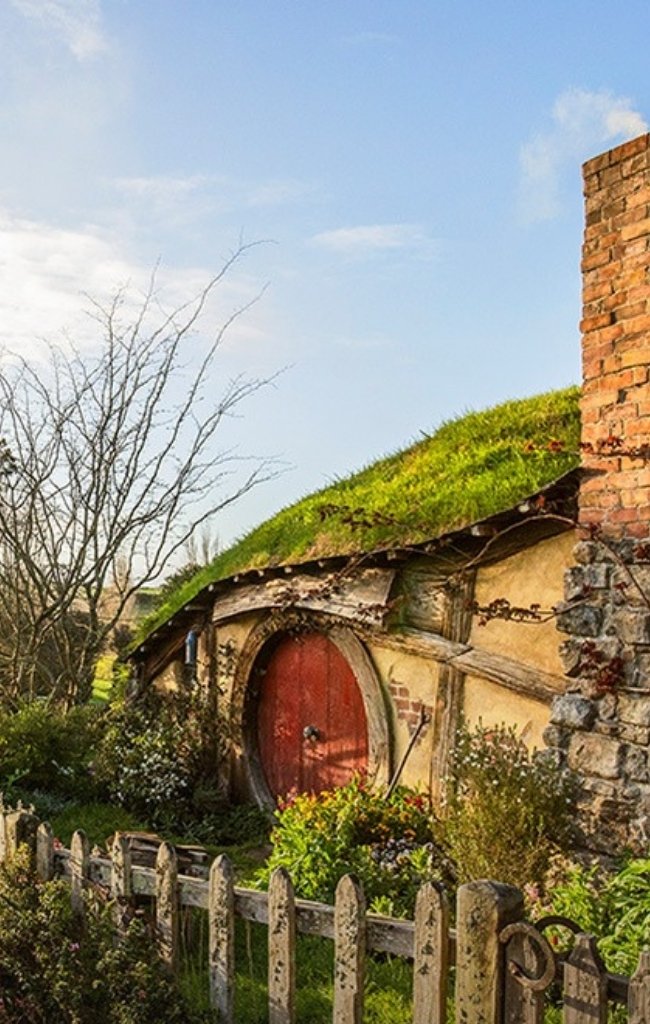 A round red door set into a grassy hillside cottage at Hobbiton