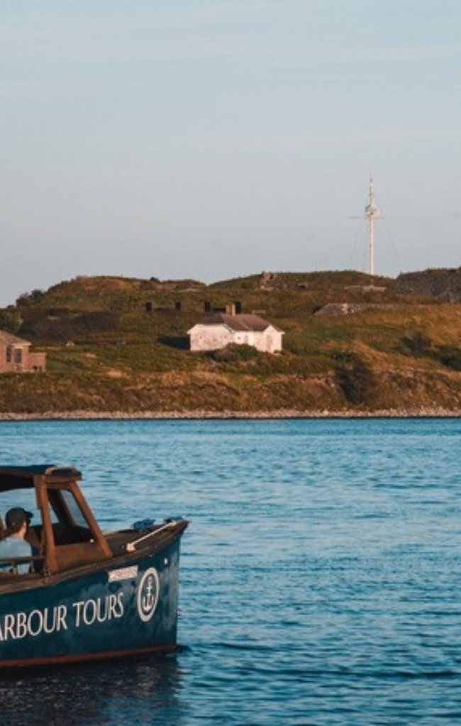 A harbour tour boat passing the lighthouse on Georges Island in Halifax