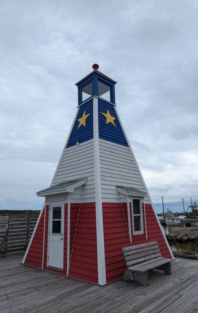 A lighthouse painted in the colors of the Acadian flag in Cape Breton